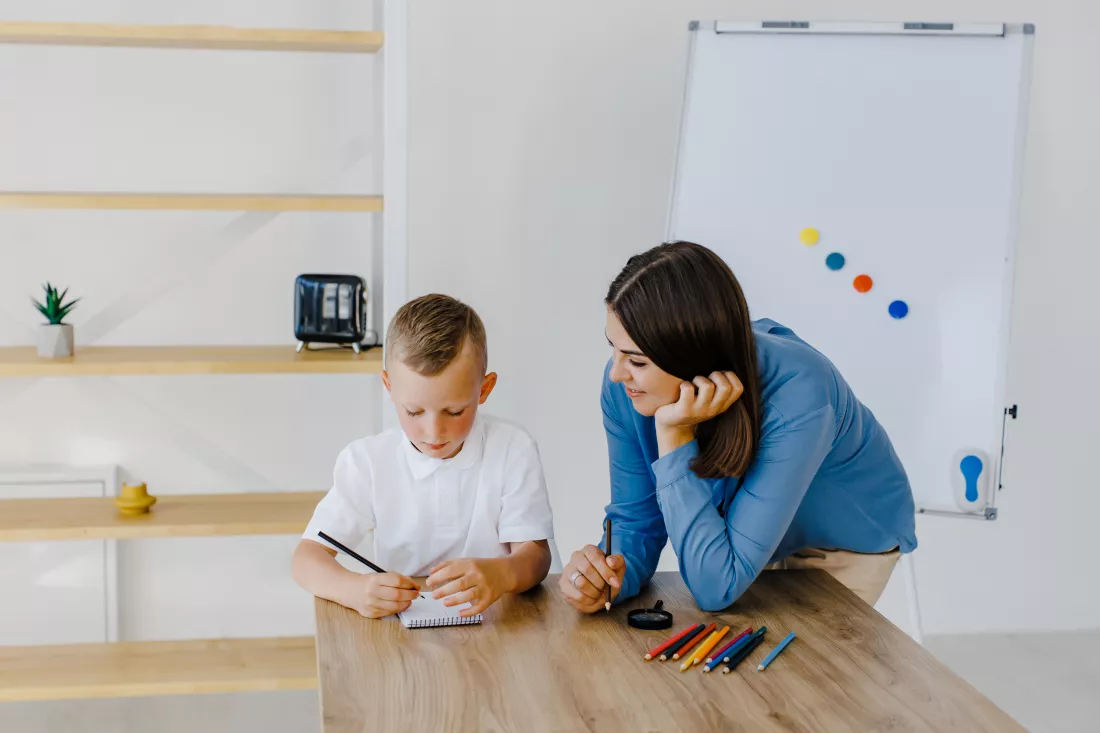 attentive-young-woman-tutor-teacher-helping-little-boy-pupil-with-studying-correct-mistakes-explain-learning-material-smiling-mother-assist-small-boy-with-home-task